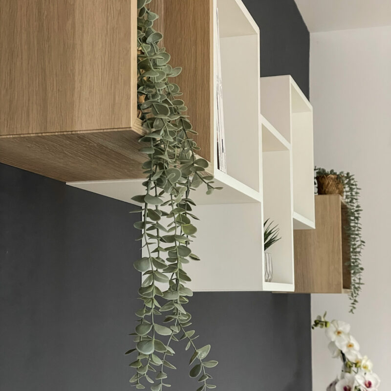 Detalle de estanterías modulares cuadradas en color madera natural y blanco, con plantas colgantes. Foto Ángela Fernández