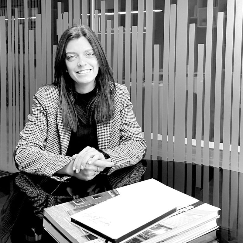 Foto en blanco y negro de Ángela Fernández sentada en una mesa de su estudio con documentación sobre la mesa.